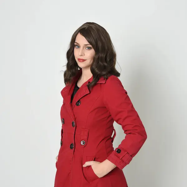 close up portrait of beautiful brunette woman model, wearing red trench jacket.isolated on white studio background. posing with  hands in pocket of jacket.