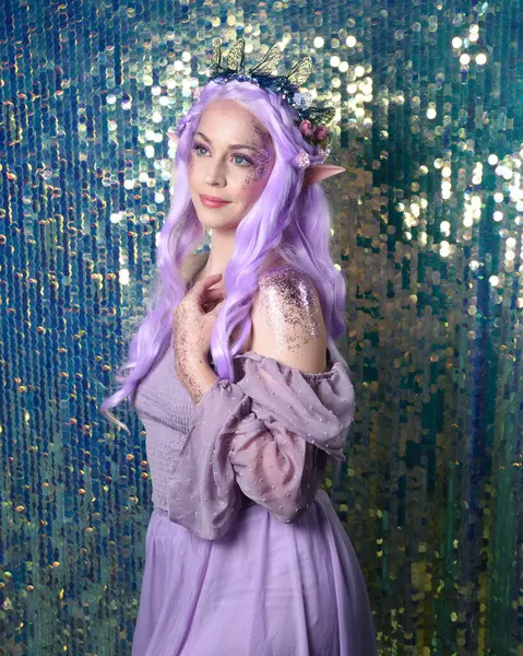 portrait of cute female model with long purple hair wearing a fantasy fairy flower crown with elf ears. Isolated on sparkling rainbow sequin background with glitter.