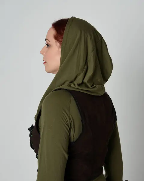 stock image Close up portrait of beautiful red haired female model, wearing green and brown medieval fantasy costume with hooded shirt and brown tunic. isolated on white studio 