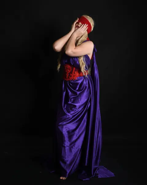 stock image Close up portrait of beautiful blonde female model wearing silk grecian toga dress and red blindfold, historical fantasy goddess,  isolated on dark studio background.