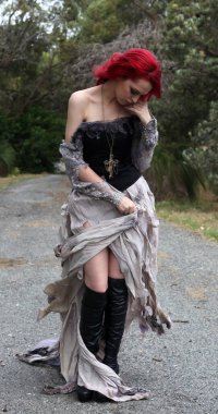 full length portrait of beautiful red haired female model figure, wearing gothic fantasy costume with torn ballgown wedding dress, black corset, leather boots.  walking pose forest scenery background. clipart