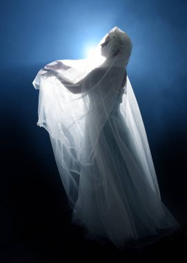 Ortaçağ masal elbisesi giymiş güzel sarışın fantezi perisi, peçeli beyaz kapüşonlu bir pelerin. dumanlı sis efektiyle izole edilmiş karanlık stüdyo arkaplanı