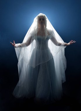 Ortaçağ masal elbisesi giymiş güzel sarışın fantezi perisi, peçeli beyaz kapüşonlu bir pelerin. dumanlı sis efektiyle izole edilmiş karanlık stüdyo arkaplanı