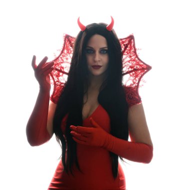 Güzel, koyu renk saçlı, gotik fantezi burlesk cadılar bayramı temalı, boynuzları ve eldivenleri olan şık kırmızı elbiseli bir mankenin siluet portresi. Beyaz stüdyoda münferit poz 
