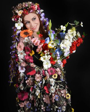 Celtic Bahar Tanrıçası Fantezi Kostümü Olarak Bir Kadın Modelinin Stüdyosu Gerçek Çiçekler ve başlıklı Beltane Pagan Mitolojisinden esinlenilerek izole edilmiş Karanlık Stüdyo Arkaplanı üzerine poz vermektedir.