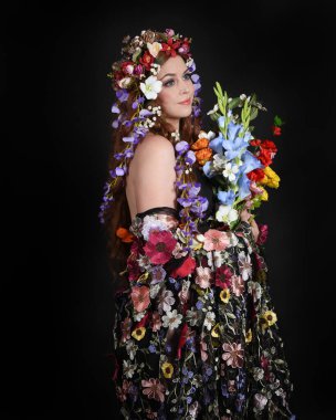 Celtic Bahar Tanrıçası Olarak Kadın Modellerinin Stüdyo Portreleri, Beltane Pagan Mitolojisinden esinlenilmiş Çiçek Fantezi Kostümleri, geri dönüp bakmaktadır. izole Karanlık Stüdyo Arkaplanı