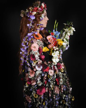 Celtic Bahar Tanrıçası Olarak Kadın Modellerinin Stüdyo Portreleri, Beltane Pagan Mitolojisinden esinlenilmiş Çiçek Fantezi Kostümleri, geri dönüp bakmaktadır. izole Karanlık Stüdyo Arkaplanı