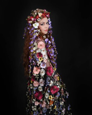 Celtic Bahar Tanrıçası Olarak Kadın Modellerinin Stüdyo Portreleri, Beltane Pagan Mitolojisinden esinlenilmiş Çiçek Fantezi Kostümleri, geri dönüp bakmaktadır. izole Karanlık Stüdyo Arkaplanı