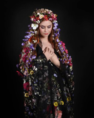 Celtic Bahar Tanrıçası Olarak Kadın Modellerinin Stüdyo Portreleri, Beltane Pagan Mitolojisinden esinlenilmiş Çiçek Fantezi Kostümleri, geri dönüp bakmaktadır. izole Karanlık Stüdyo Arkaplanı