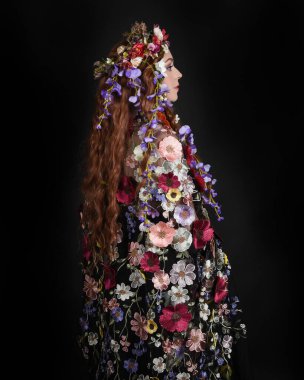 Celtic Bahar Tanrıçası Olarak Kadın Modellerinin Stüdyo Portreleri, Beltane Pagan Mitolojisinden esinlenilmiş Çiçek Fantezi Kostümleri, geri dönüp bakmaktadır. izole Karanlık Stüdyo Arkaplanı