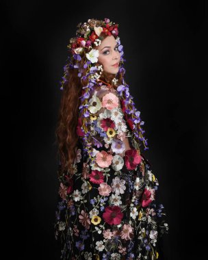 Celtic Bahar Tanrıçası Olarak Kadın Modellerinin Stüdyo Portreleri, Beltane Pagan Mitolojisinden esinlenilmiş Çiçek Fantezi Kostümleri, geri dönüp bakmaktadır. izole Karanlık Stüdyo Arkaplanı