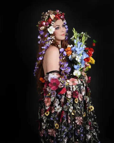 Celtic Bahar Tanrıçası Olarak Kadın Modellerinin Stüdyo Portreleri, Beltane Pagan Mitolojisinden esinlenilmiş Çiçek Fantezi Kostümleri, geri dönüp bakmaktadır. izole Karanlık Stüdyo Arkaplanı