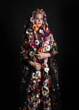 Celtic Bahar Tanrıçası Olarak Kadın Model Stüdyo Portreleri, Beltane Pagan Mitolojisinden esinlenerek Çiçek Fantezi Pelerini Kostümü. Kol hareketleriyle klasik poz, izole edilmiş Karanlık Arkaplan