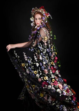 Celtic Bahar Tanrıçası Olarak Kadın Model Stüdyo Portreleri, Beltane Pagan Mitolojisinden esinlenerek Çiçek Fantezi Pelerini Kostümü. Kol hareketleriyle klasik poz, izole edilmiş Karanlık Arkaplan