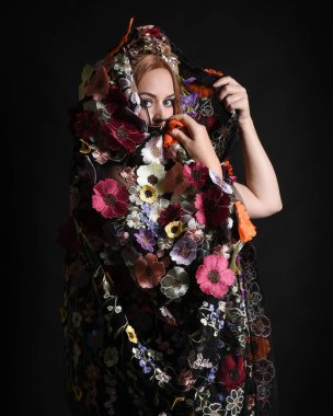 Celtic Bahar Tanrıçası Olarak Kadın Model Stüdyo Portreleri, Beltane Pagan Mitolojisinden esinlenerek Çiçek Fantezi Pelerini Kostümü. Kol hareketleriyle klasik poz, izole edilmiş Karanlık Arkaplan