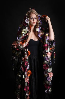 Celtic Bahar Tanrıçası Olarak Kadın Model Stüdyo Portreleri, Beltane Pagan Mitolojisinden esinlenerek Çiçek Fantezi Pelerini Kostümü. Kol hareketleriyle klasik poz, izole edilmiş Karanlık Arkaplan