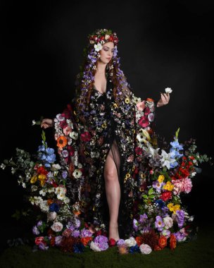 Celtic Bahar Tanrıçası Olarak Kadın Modellerinin Stüdyo Portreleri, Beltane Pagan Mitolojisinden esinlenilmiş Çiçek Peri Fantezi Kostümü. İzole edilmiş Karanlık Stüdyo Arkaplanda Pelerinli Klasik Duruş