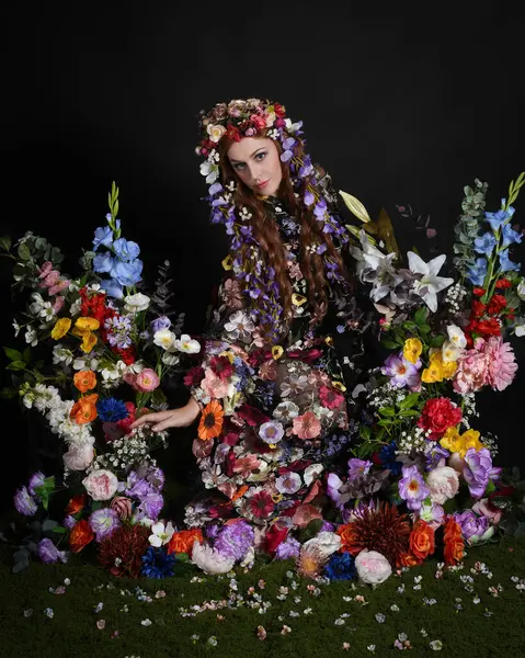Celtic Bahar Tanrıçası Olarak Kadın Modellerinin Stüdyo Portreleri, Beltane Pagan Mitolojisinden esinlenilmiş Çiçek Peri Fantezi Kostümü. İzole edilmiş Karanlık Stüdyo Arkaplan 'da klasik oturma pozu