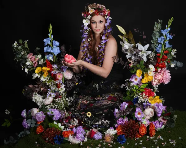 Celtic Bahar Tanrıçası Olarak Kadın Modellerinin Stüdyo Portreleri, Beltane Pagan Mitolojisinden esinlenilmiş Çiçek Peri Fantezi Kostümü. İzole edilmiş Karanlık Stüdyo Arkaplan 'da klasik oturma pozu