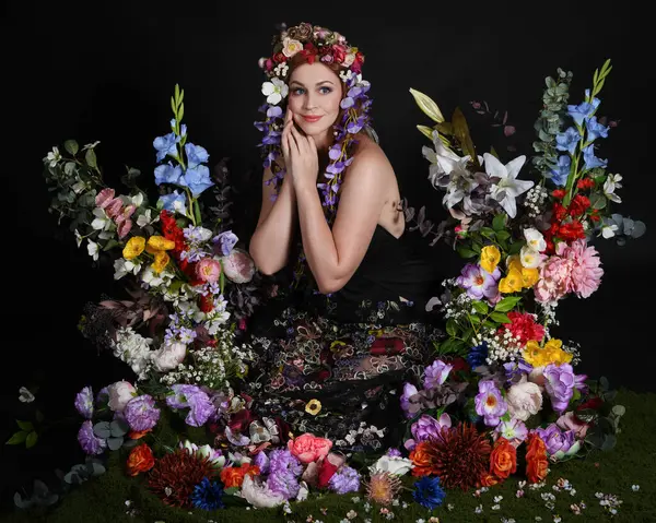 Celtic Bahar Tanrıçası Olarak Kadın Modellerinin Stüdyo Portreleri, Beltane Pagan Mitolojisinden esinlenilmiş Çiçek Peri Fantezi Kostümü. İzole edilmiş Karanlık Stüdyo Arkaplan 'da klasik oturma pozu