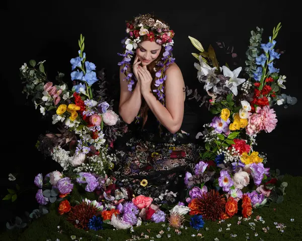 Celtic Bahar Tanrıçası Olarak Kadın Modellerinin Stüdyo Portreleri, Beltane Pagan Mitolojisinden esinlenilmiş Çiçek Peri Fantezi Kostümü. İzole edilmiş Karanlık Stüdyo Arkaplan 'da klasik oturma pozu