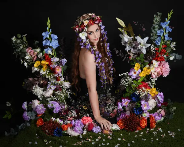 Celtic Bahar Tanrıçası Olarak Kadın Modellerinin Stüdyo Portreleri, Beltane Pagan Mitolojisinden esinlenilmiş Çiçek Peri Fantezi Kostümü. İzole edilmiş Karanlık Stüdyo Arkaplan 'da klasik oturma pozu