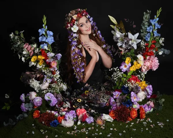 Celtic Bahar Tanrıçası Olarak Kadın Modellerinin Stüdyo Portreleri, Beltane Pagan Mitolojisinden esinlenilmiş Çiçek Peri Fantezi Kostümü. İzole edilmiş Karanlık Stüdyo Arkaplan 'da klasik oturma pozu