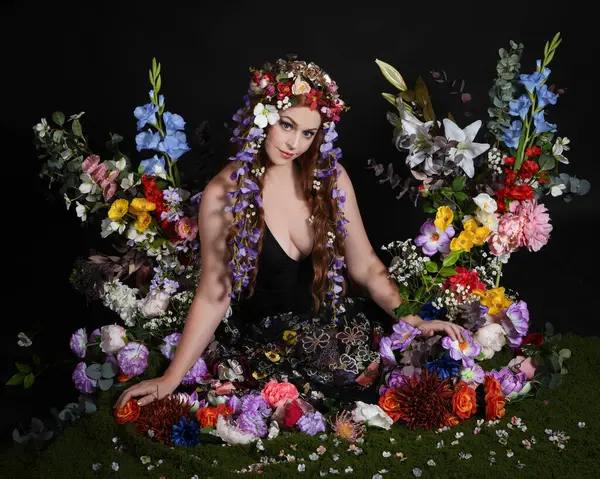 Celtic Bahar Tanrıçası Olarak Kadın Modellerinin Stüdyo Portreleri, Beltane Pagan Mitolojisinden esinlenilmiş Çiçek Peri Fantezi Kostümü. İzole edilmiş Karanlık Stüdyo Arkaplan 'da klasik oturma pozu