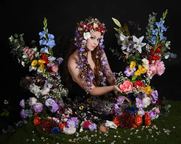 Celtic Bahar Tanrıçası Olarak Kadın Modellerinin Stüdyo Portreleri, Beltane Pagan Mitolojisinden esinlenilmiş Çiçek Peri Fantezi Kostümü. İzole edilmiş Karanlık Stüdyo Arkaplan 'da klasik oturma pozu