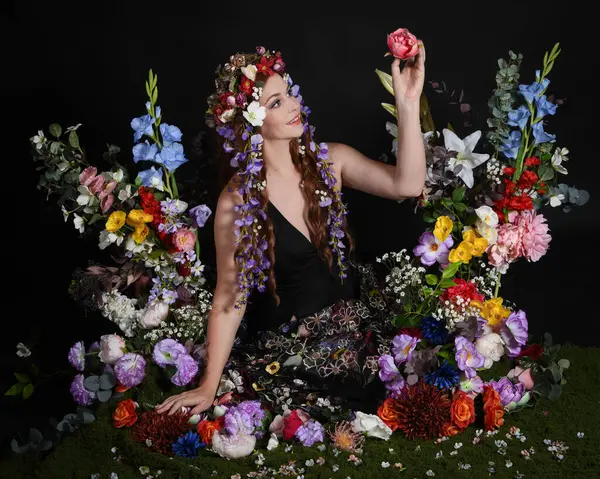 Celtic Bahar Tanrıçası Olarak Kadın Modellerinin Stüdyo Portreleri, Beltane Pagan Mitolojisinden esinlenilmiş Çiçek Peri Fantezi Kostümü. İzole edilmiş Karanlık Stüdyo Arkaplan 'da klasik oturma pozu