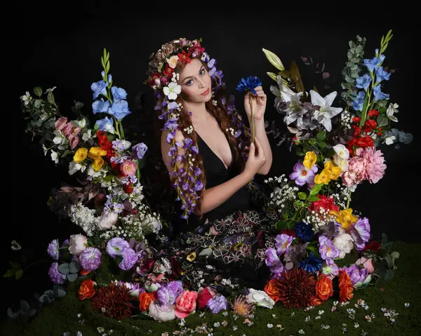 Celtic Bahar Tanrıçası Olarak Kadın Modellerinin Stüdyo Portreleri, Beltane Pagan Mitolojisinden esinlenilmiş Çiçek Peri Fantezi Kostümü. İzole edilmiş Karanlık Stüdyo Arkaplan 'da klasik oturma pozu