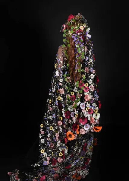 Celtic Bahar Tanrıçası Olarak Kadın Model Stüdyo Portreleri, Beltane Pagan Mitolojisinden esinlenerek Çiçek Fantezi Pelerini Kostümü. Kol hareketleriyle klasik poz, izole edilmiş Karanlık Arkaplan