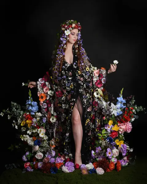 Celtic Bahar Tanrıçası Olarak Kadın Modellerinin Stüdyo Portreleri, Beltane Pagan Mitolojisinden esinlenilmiş Çiçek Peri Fantezi Kostümü. İzole edilmiş Karanlık Stüdyo Arkaplanda Pelerinli Klasik Duruş