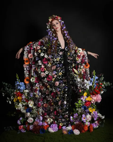 Celtic Bahar Tanrıçası Olarak Kadın Modellerinin Stüdyo Portreleri, Beltane Pagan Mitolojisinden esinlenilmiş Çiçek Peri Fantezi Kostümü. İzole edilmiş Karanlık Stüdyo Arkaplanda Pelerinli Klasik Duruş