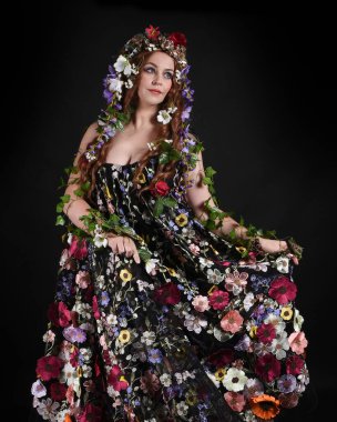 Kelt Bahar Tanrıçası Olarak Güzel Kadın Modeli Portreleri, Beltane Pagan Mitolojisinden esinlenerek Çiçek Fantezi Pelerini Kostümü. izole Karanlık Stüdyo Arkaplanı