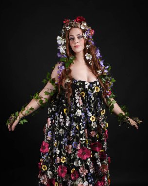 Kelt Bahar Tanrıçası Olarak Güzel Kadın Modeli Portreleri, Beltane Pagan Mitolojisinden esinlenerek Çiçek Fantezi Pelerini Kostümü. izole Karanlık Stüdyo Arkaplanı