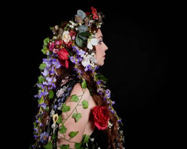 Kelt Bahar Tanrıçası Olarak Güzel Kadın Modeli Portreleri, Beltane Pagan Mitolojisinden esinlenerek Çiçek Fantezi Pelerini Kostümü. izole Karanlık Stüdyo Arkaplanı