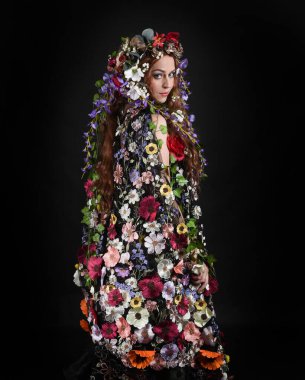 Kelt Bahar Tanrıçası Olarak Güzel Kadın Modeli Portreleri, Beltane Pagan Mitolojisinden esinlenerek Çiçek Fantezi Pelerini Kostümü. izole Karanlık Stüdyo Arkaplanı