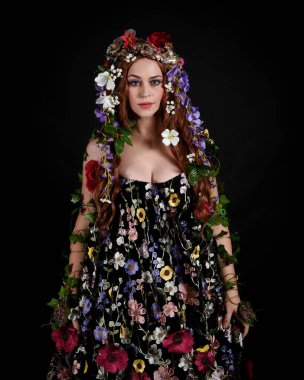 Kelt Bahar Tanrıçası Olarak Güzel Kadın Modeli Portreleri, Beltane Pagan Mitolojisinden esinlenerek Çiçek Fantezi Pelerini Kostümü. izole Karanlık Stüdyo Arkaplanı