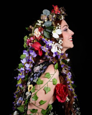Kelt Bahar Tanrıçası Olarak Güzel Kadın Modeli Portreleri, Beltane Pagan Mitolojisinden esinlenerek Çiçek Fantezi Pelerini Kostümü. izole Karanlık Stüdyo Arkaplanı