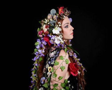 Kelt Bahar Tanrıçası Olarak Güzel Kadın Modeli Portreleri, Beltane Pagan Mitolojisinden esinlenerek Çiçek Fantezi Pelerini Kostümü. izole Karanlık Stüdyo Arkaplanı