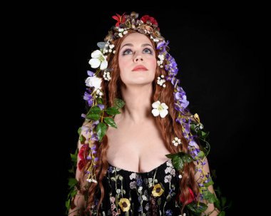 Kelt Bahar Tanrıçası Olarak Güzel Kadın Modeli Portreleri, Beltane Pagan Mitolojisinden esinlenerek Çiçek Fantezi Pelerini Kostümü. izole Karanlık Stüdyo Arkaplanı