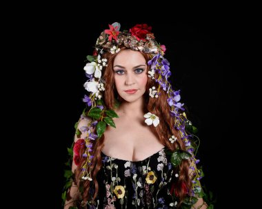 Kelt Bahar Tanrıçası Olarak Güzel Kadın Modeli Portreleri, Beltane Pagan Mitolojisinden esinlenerek Çiçek Fantezi Pelerini Kostümü. izole Karanlık Stüdyo Arkaplanı