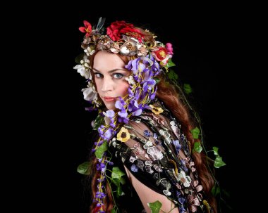 Kelt Bahar Tanrıçası Olarak Güzel Kadın Modeli Portreleri, Beltane Pagan Mitolojisinden esinlenerek Çiçek Fantezi Pelerini Kostümü. izole Karanlık Stüdyo Arkaplanı