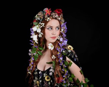 Kelt Bahar Tanrıçası Olarak Güzel Kadın Modeli Portreleri, Beltane Pagan Mitolojisinden esinlenerek Çiçek Fantezi Pelerini Kostümü. izole Karanlık Stüdyo Arkaplanı