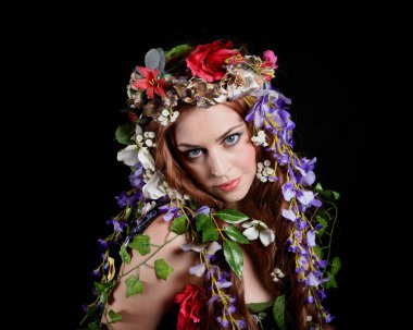 Kelt Bahar Tanrıçası Olarak Güzel Kadın Modeli Portreleri, Beltane Pagan Mitolojisinden esinlenerek Çiçek Fantezi Pelerini Kostümü. izole Karanlık Stüdyo Arkaplanı