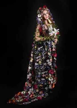Kelt Bahar Tanrıçası Olarak Kadın Modeli 'nin Portresi Beltane Pagan Mitolojisinden esinlenerek Çiçek Fantezi Pelerini Kostümü. Uzaklaşmak, geriye doğru poz vermek, Karanlık Stüdyo Arkaplanı 'nda soyutlanmak