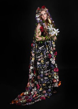Kelt Bahar Tanrıçası Olarak Kadın Modeli 'nin Portresi Beltane Pagan Mitolojisinden esinlenerek Çiçek Fantezi Pelerini Kostümü. Uzaklaşmak, geriye doğru poz vermek, Karanlık Stüdyo Arkaplanı 'nda soyutlanmak