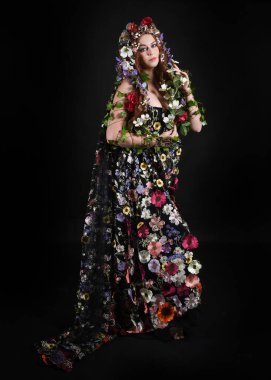 Kelt Bahar Tanrıçası Olarak Kadın Modeli 'nin Portresi Beltane Pagan Mitolojisinden esinlenerek Çiçek Fantezi Pelerini Kostümü. Uzaklaşmak, geriye doğru poz vermek, Karanlık Stüdyo Arkaplanı 'nda soyutlanmak