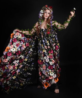 Kelt Bahar Tanrıçası Olarak Kadın Modeli 'nin Portresi Beltane Pagan Mitolojisinden esinlenerek Çiçek Fantezi Pelerini Kostümü. Uzaklaşmak, geriye doğru poz vermek, Karanlık Stüdyo Arkaplanı 'nda soyutlanmak